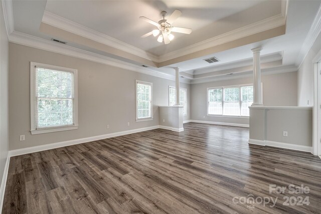 unfurnished living room with a raised ceiling, a healthy amount of sunlight, hardwood / wood-style flooring, and crown molding