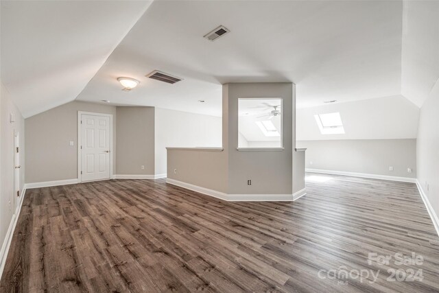 bonus room featuring hardwood / wood-style floors, vaulted ceiling with skylight, and ceiling fan