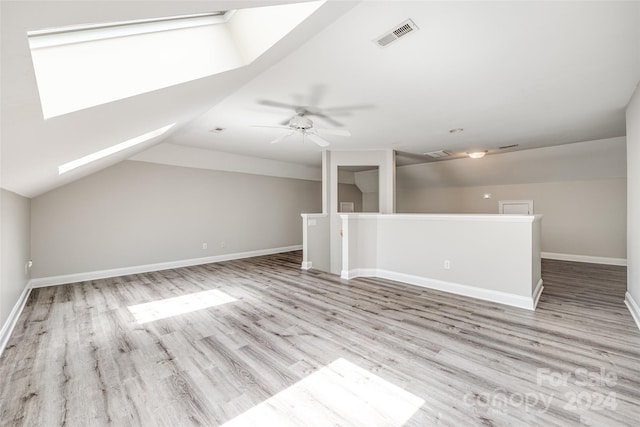 bonus room featuring ceiling fan, vaulted ceiling with skylight, and light hardwood / wood-style floors