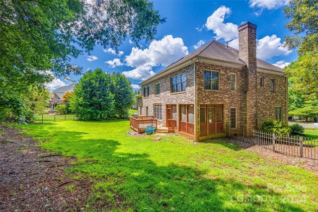 back of property featuring a deck and a yard