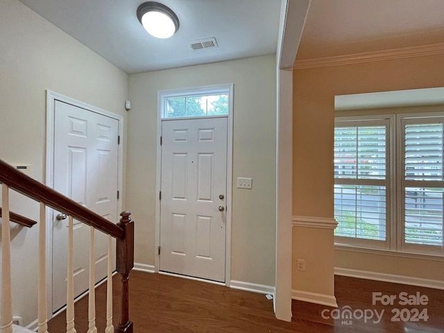 entrance foyer with ornamental molding and dark wood-type flooring