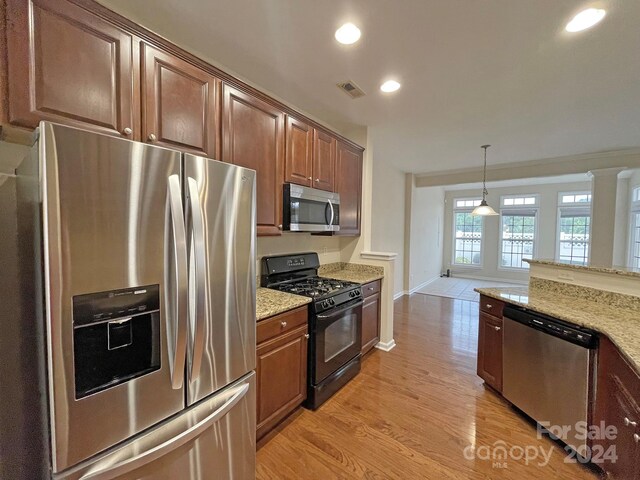 kitchen featuring light hardwood / wood-style floors, stainless steel appliances, light stone counters, and pendant lighting