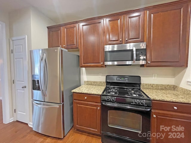 kitchen with light hardwood / wood-style floors, stainless steel appliances, and light stone counters