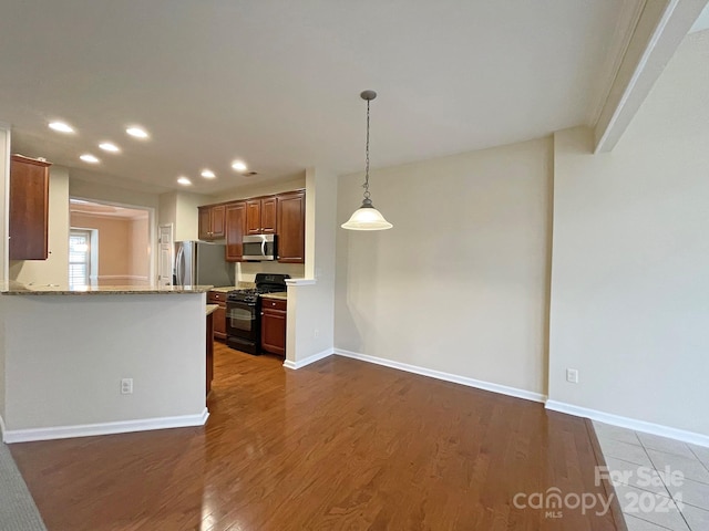 kitchen featuring light stone countertops, appliances with stainless steel finishes, dark hardwood / wood-style flooring, and kitchen peninsula