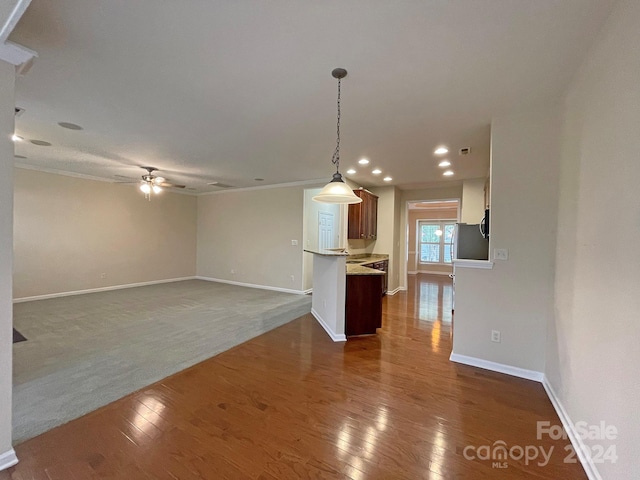 unfurnished living room featuring ornamental molding, dark wood-type flooring, and ceiling fan