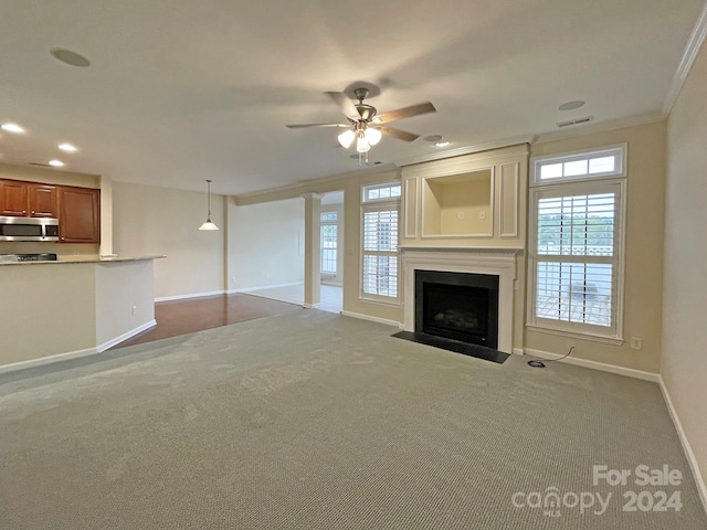 unfurnished living room featuring carpet flooring, ornamental molding, and a wealth of natural light