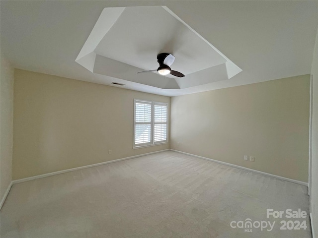 carpeted empty room with ceiling fan and a tray ceiling