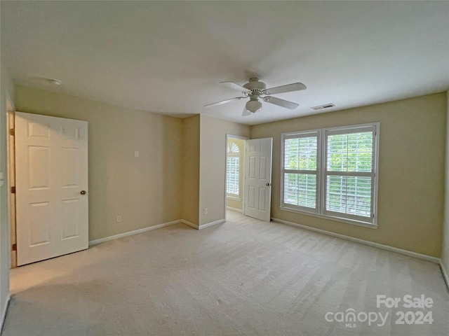 spare room featuring light carpet and ceiling fan