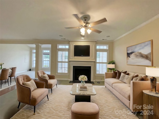 living room featuring ornate columns, ornamental molding, light wood-type flooring, a fireplace, and ceiling fan