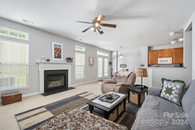 living room with ceiling fan, carpet flooring, and plenty of natural light