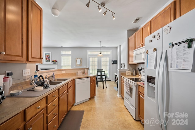 kitchen with pendant lighting, white appliances, sink, kitchen peninsula, and track lighting