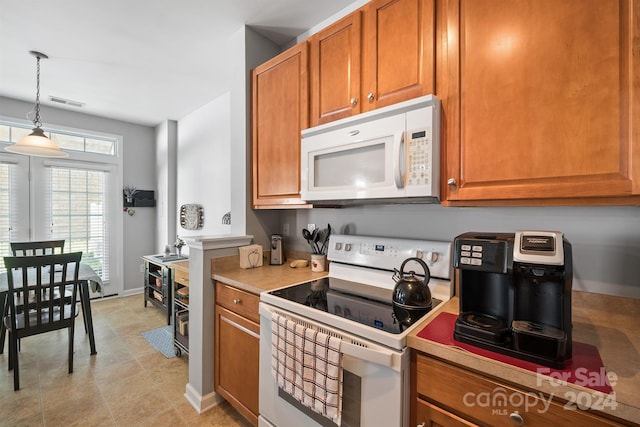 kitchen featuring hanging light fixtures, white appliances, and light tile patterned floors