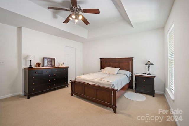 carpeted bedroom with ceiling fan and a raised ceiling