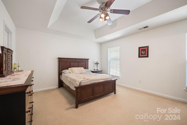 bedroom featuring light carpet, ceiling fan, and a raised ceiling