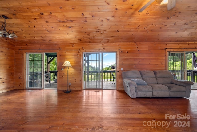 unfurnished living room with wood ceiling, wood walls, hardwood / wood-style floors, and ceiling fan