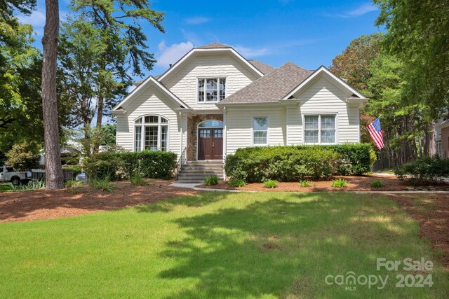view of front of house featuring a shingled roof and a front lawn