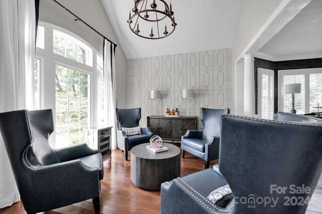 living room featuring ornate columns, wood finished floors, tile walls, and plenty of natural light