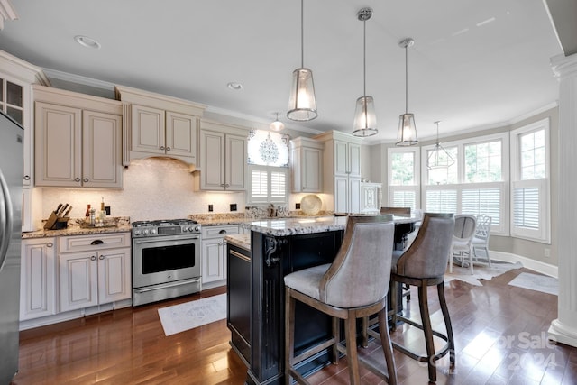 kitchen featuring light stone counters, a kitchen island, decorative light fixtures, dark wood-type flooring, and appliances with stainless steel finishes