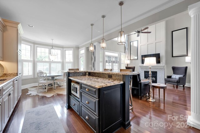 kitchen featuring a breakfast bar, dark wood-style floors, white microwave, and crown molding