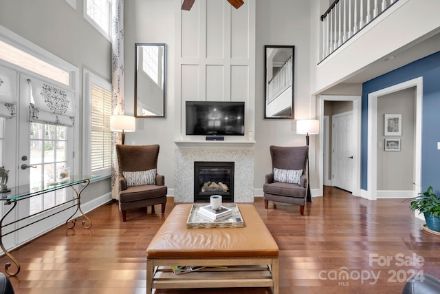 living room featuring ceiling fan, a fireplace, dark hardwood / wood-style floors, and a high ceiling