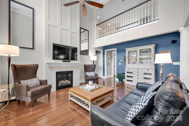 living room featuring wood-type flooring, ceiling fan, and a high ceiling