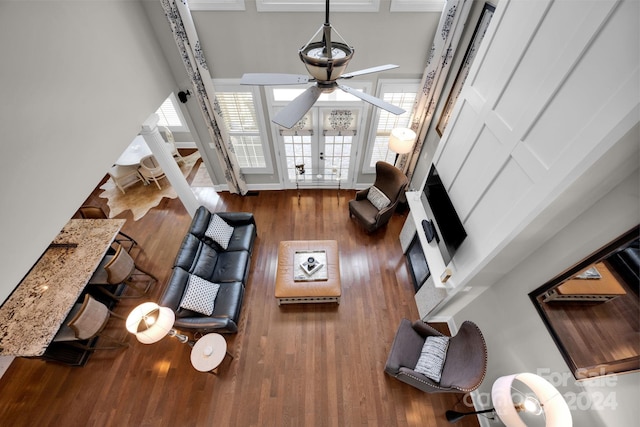 living room with a high ceiling, dark hardwood / wood-style flooring, and ceiling fan