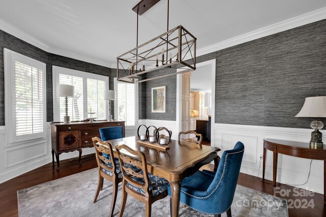 dining area featuring wallpapered walls, a wainscoted wall, ornamental molding, and wood finished floors