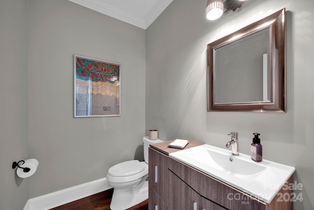 bathroom with wood-type flooring, ornamental molding, vanity, and toilet