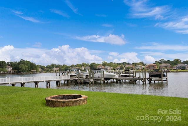 dock area with a fire pit, a lawn, and a water view