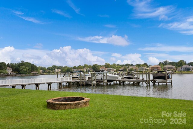 view of dock featuring a water view, a lawn, boat lift, and a fire pit