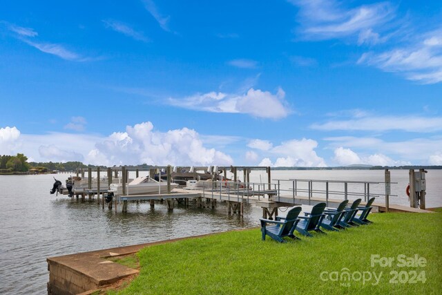 dock area with boat lift, a water view, and a yard