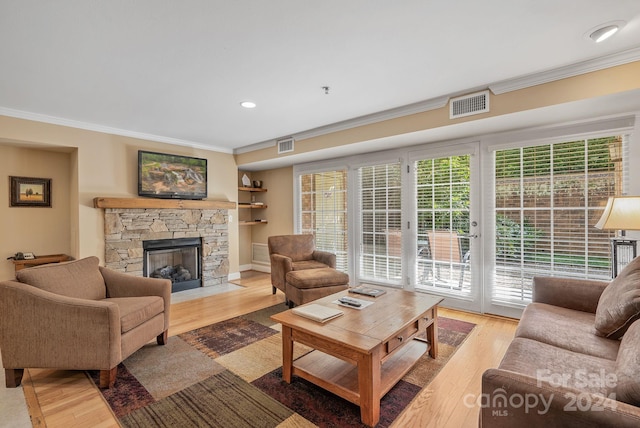 living room with a stone fireplace, light wood-type flooring, and ornamental molding