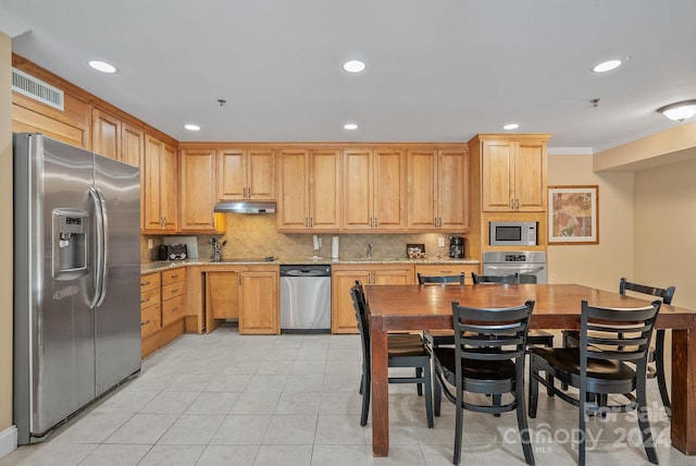 kitchen featuring tasteful backsplash, visible vents, under cabinet range hood, light stone counters, and appliances with stainless steel finishes