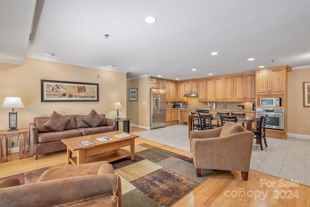 living area with recessed lighting, light wood-style flooring, baseboards, and ornamental molding