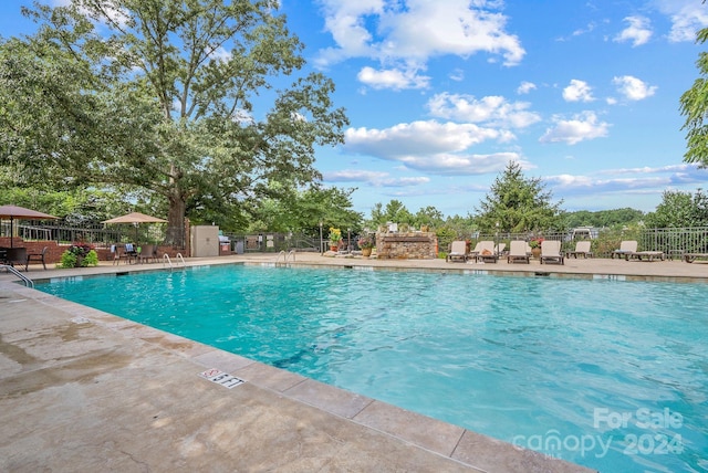 community pool with a patio and fence