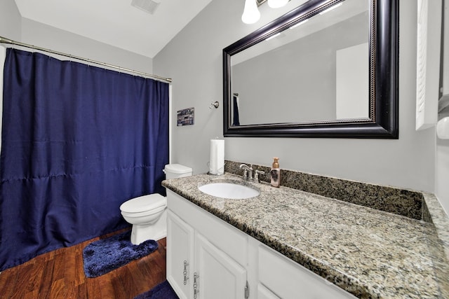 bathroom featuring hardwood / wood-style flooring, vaulted ceiling, toilet, and vanity