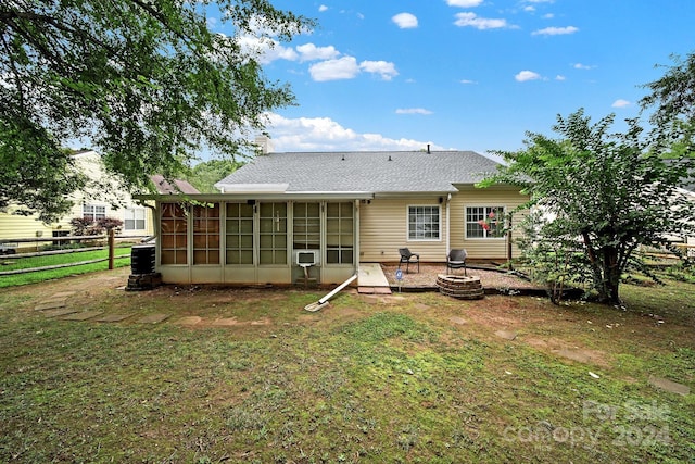 rear view of house featuring a yard, a sunroom, a patio, and a fire pit