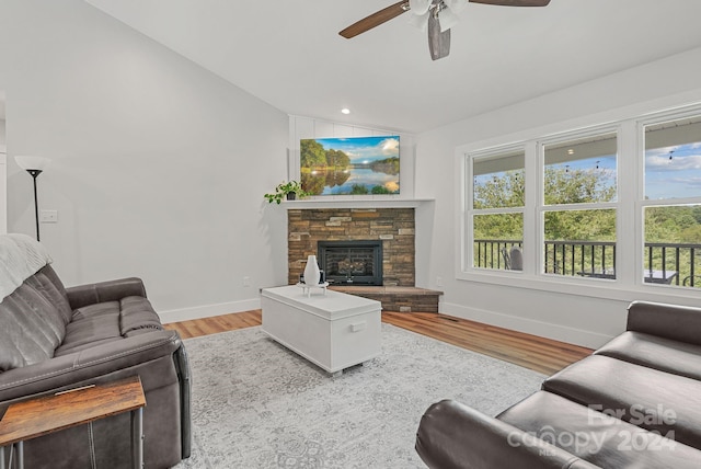 living room with a fireplace, light hardwood / wood-style flooring, vaulted ceiling, and ceiling fan