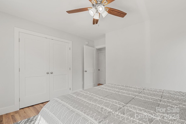 bedroom with light wood-type flooring, ceiling fan, and a closet