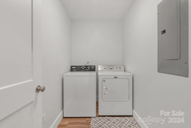 laundry room featuring light hardwood / wood-style floors, washer and dryer, and electric panel