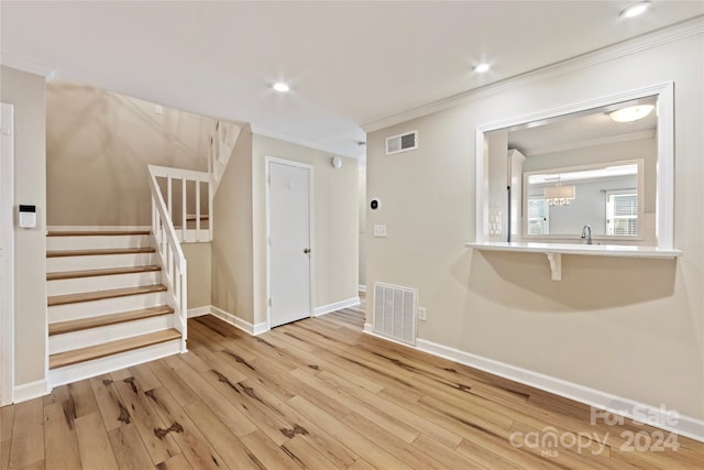 interior space with ornamental molding, sink, and light wood-type flooring