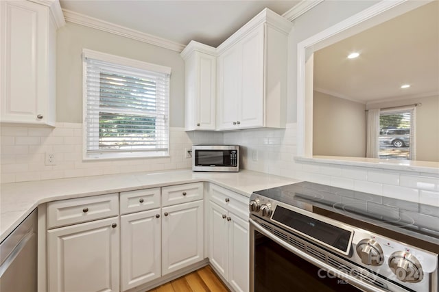 kitchen with a wealth of natural light, white cabinets, light wood-type flooring, and stainless steel appliances