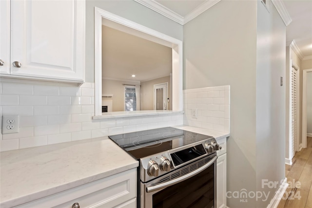 kitchen featuring crown molding, light hardwood / wood-style flooring, electric range, and tasteful backsplash