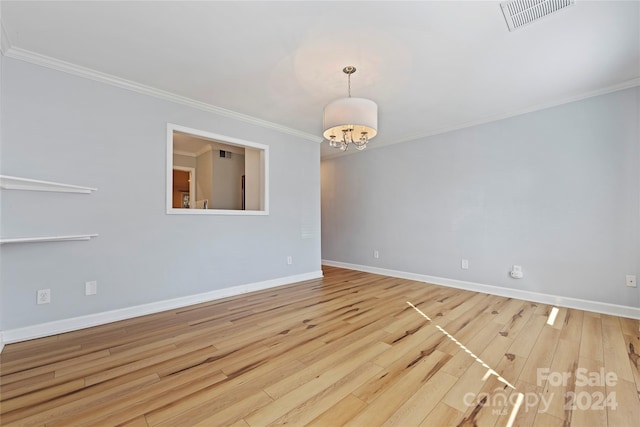 spare room with a chandelier, crown molding, and light hardwood / wood-style floors