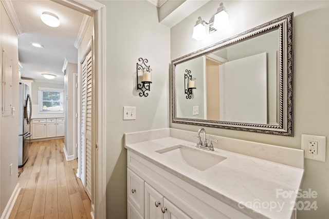 bathroom with ornamental molding, vanity, and hardwood / wood-style floors