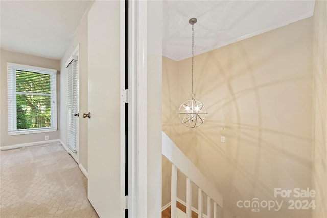 hallway featuring an inviting chandelier and carpet