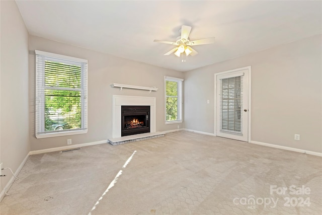 unfurnished living room with light colored carpet and ceiling fan