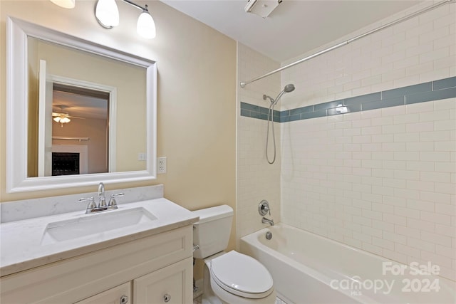 full bathroom with ceiling fan, toilet, vanity, and tiled shower / bath