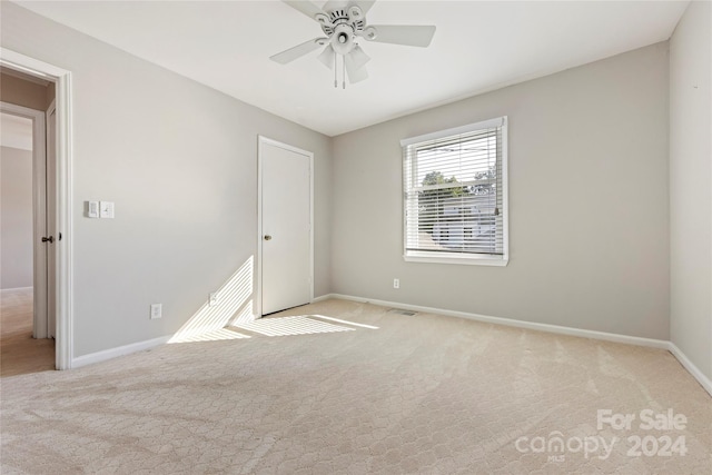 spare room with light colored carpet and ceiling fan