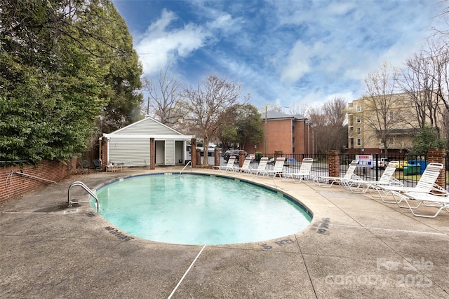 community pool with a patio area and fence